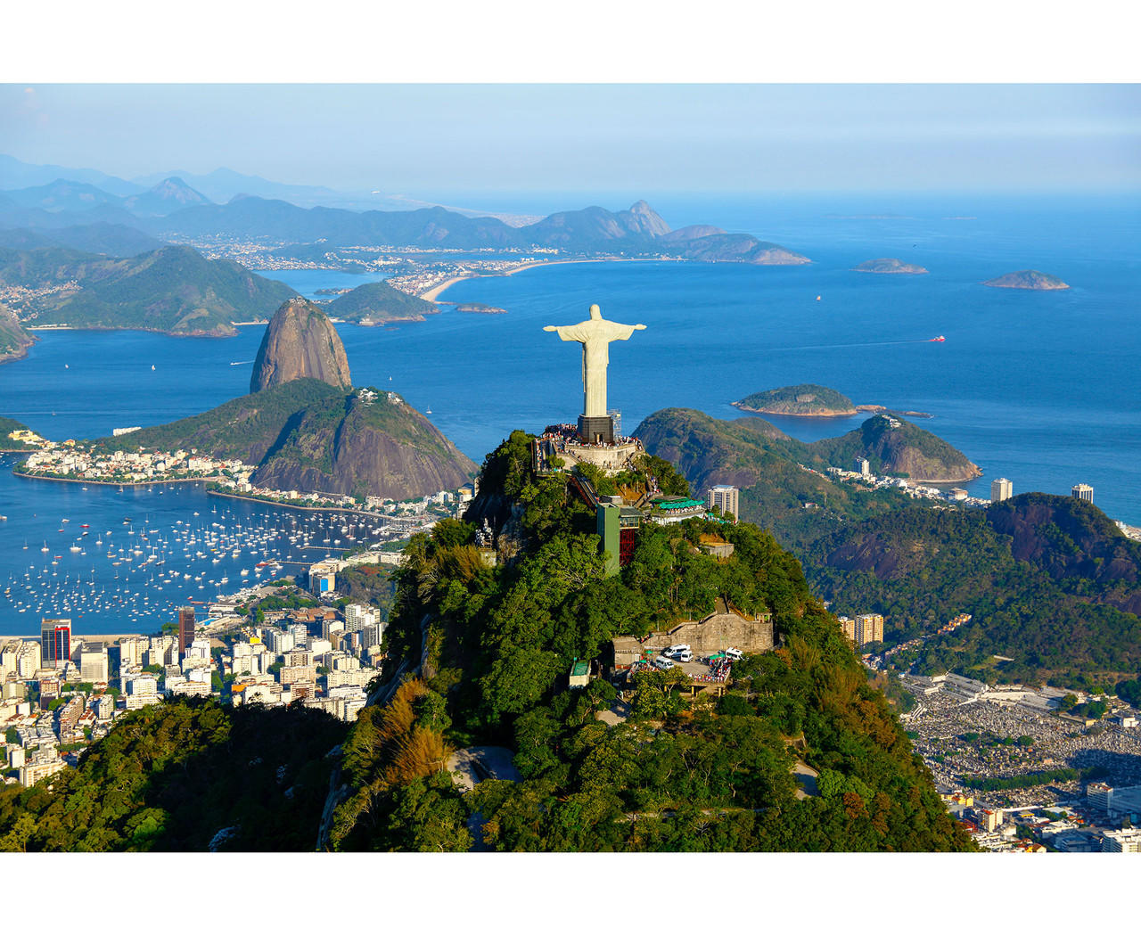 Aerial view of Christ the Redeemer statue overlooking Rio de Janeiro with Guanabara Bay and mountains in the background